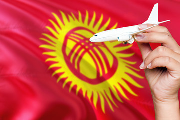 Kyrgyzstan travel concept. Woman holding a miniature plane on national flag background. Holiday and...