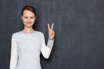 Portrait of happy young woman showing peace or victory gesture