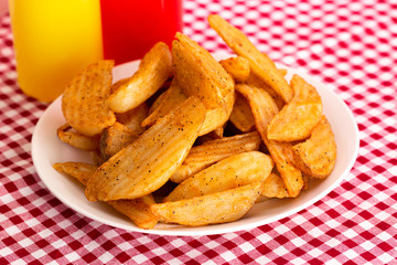 Plate of Spiced Potato Wedges on a Red Gingham Table Cloth