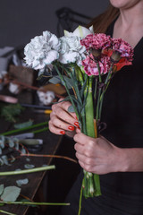 Woman florist makes a bouquet to order, concept of own flower business, selective focus