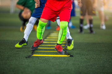 Kid soccer players are jogging and jump between marker for football training. Ladder drills exercises for football soccer team. Kid player exercises on ladder drills.