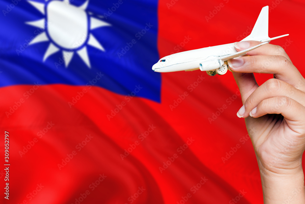 Wall mural Taiwan travel concept. Woman holding a miniature plane on national flag background. Holiday and voyage theme with copy space for text.