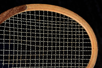 Close-up and detail shot of an old wooden tennis racket in front of dark background