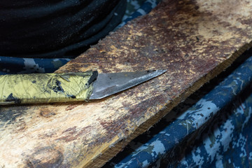 Shoe repair. Old sharp knife lying on a wooden table. Working place of a shoemaker closeup. Wooden background.