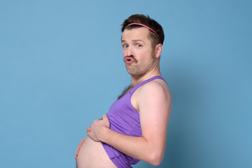 Fat funny caucasian young man with mustache is posing in studio showing big tummy