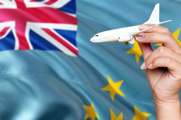Tuvalu travel concept. Woman holding a miniature plane on national flag background. Holiday and voyage theme with copy space for text.