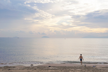 Young man going for a swim in the ocean at sunset 