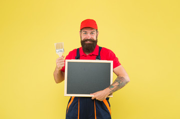 Painting works. Bearded decorator hold blackboard copy space. Repair tips. Happy hours. Man worker with paint brush. Builder regular worker. Repair and renovation. Quick repair. Creative decorator