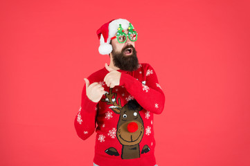 Pre-Christmas Delivery. bearded man santa hat red wall. merry christmas. male in xmas party glasses. happy new year. funny hipster knitted sweater. warm cloth for cold weather. winter holiday season