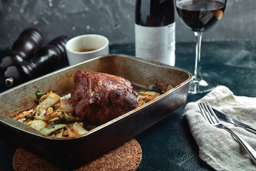 Baked meat and potatoes. A delicious and hearty meal. A large baked piece of meat. Cooked hot food.