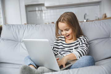 Little kid girl at home childhood concept playing game on laptop