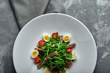 Tasty italian salad of beef tongue with eggs, arugula, tomato, spices and sauce