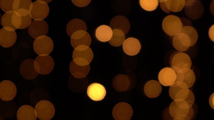 Defocused blurry glowing golden lights of led holiday garlands shining in darkness of night. Abstract festive bokeh video background. Real time 4k footage. - Powered by Adobe