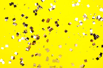 Falling silver confetti on yellow backdrop. Holiday concept.
