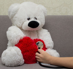 the child plays a doctor and listens to the heart of a teddy bear with a stethoscope