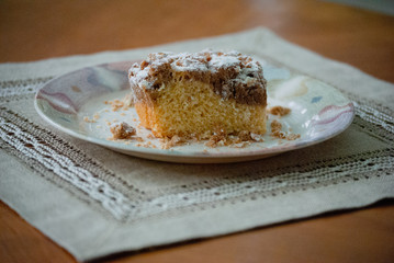 Single piece of coffee crumb cake, streusel, on a plate with a bokeh background with space for copy