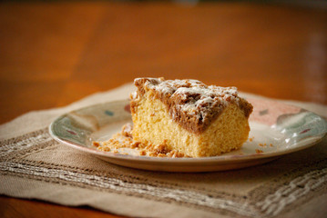 Single piece of coffee crumb cake, streusel, on a plate with a bokeh background with space for copy
