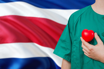 Costa Rica veterinary clinic concept. Veterinarian is holding plastic heart in green uniform on...