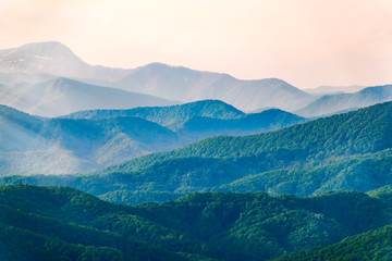 Layers of mountains in the haze during sunset. Beautiful sunset in the hills and mountains. Beautiful sunset in a hilly valley with fog in the lowlands.