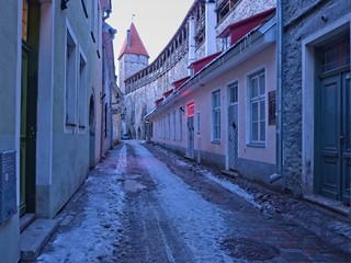 Narrow Alleyway in the medieval old town of Tallinn at dusk with a tower of the city wall in the background