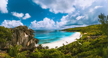 Panoramic view of beautiful Grand Anse beach on La Digue island in Seychelles. Blue lagoon with white clouds above
