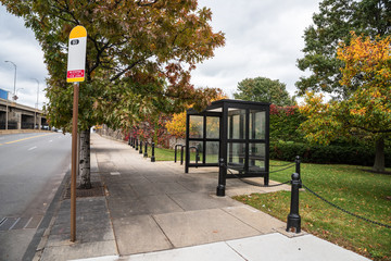 Deserted bus stop with a glass shed along a street on a cloudy autumn day