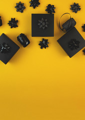 Black gift box on a yellow background, decorated with a textured bow. Typically used for birthday, anniversary presents, gift cards, post cards.