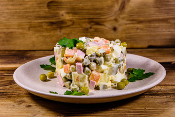 Ceramic plate with russian traditional new year salad olivier on a wooden table