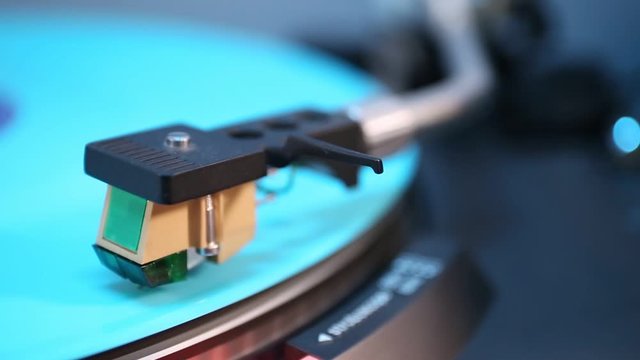 Phono cartridge close up on spinning turntable.