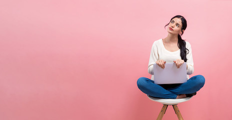 Obraz premium Young woman using a laptop computer on a pink background