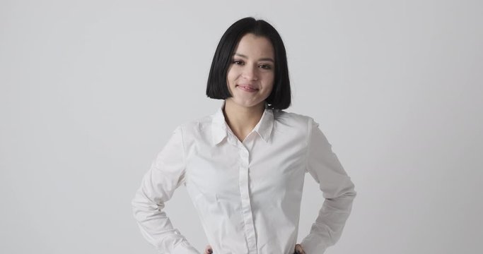 Happy young woman with short hair and arms akimbo over white background