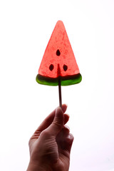 Woman hand holding watermelon lollipop on white background. 