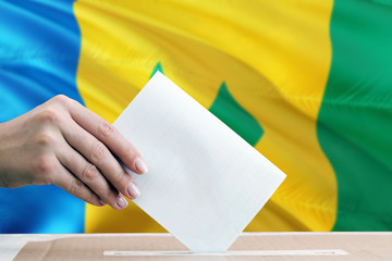 Saint Vincent And The Grenadines election concept. Side view woman putting a ballot in a box on...