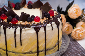 Beautiful festive cake with chocolate icing and marmalade on a background of flowers