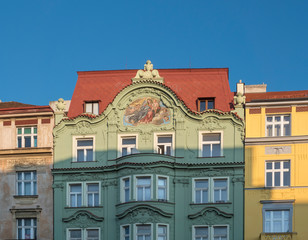 Fototapeta na wymiar Beautiful green, yellow and pink ancient historical residential house facades with fresco at Letna, Prague, Czech Republic. Blue sky background