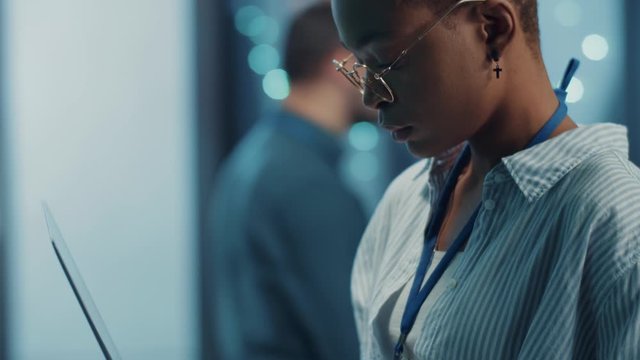 Close-up pretty smart woman IT specialist analyzing server system maintenance with laptop computer in database cabinet. Data center worker. Multi-ethnic people.