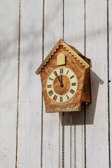 Old clock on a wooden light wall. Vintage clock.