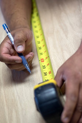 Closeup of tape measure and hands on wood