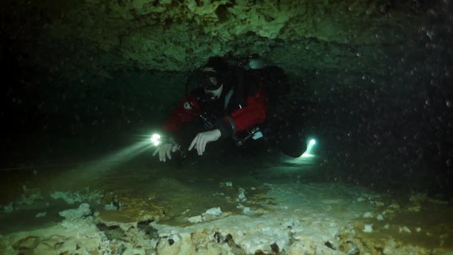 Divers in rocks of underwater cave Yucatan Mexico cenotes. Diving in clean and clear underground water.