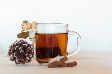 Cup of tea decorated with sweet angel, pine cone and cookies on white wooden table