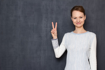 Portrait of happy girl showing two fingers as peace or victory gesture
