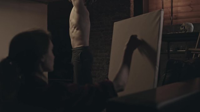 Woman is drawing bearded muscular man, focus on man, slow motion