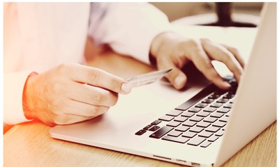 Businessman working on laptop and holds card