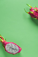 Fresh organic dragonfruit (pitaya or pitahaya) cut in half on green mint background. Creative flat...