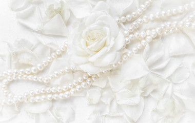 Obraz na płótnie Canvas Beautiful white rose and pearl necklace on a background of petals. Ideal for greeting cards for wedding, birthday, Valentine's Day, Mother's Day