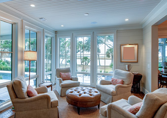 Beautiful sitting room interior with view out onto waterfront property. - obrazy, fototapety, plakaty