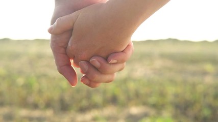 The hands of people in love hold on to each other in light of the sun. A man and a woman hold hands and walk. Theme of love and happiness of the family. Silhouettes go into focus in a bright future