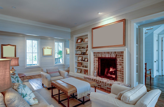 Beautiful living room in expensive home with burning fireplace and large blank picture over the mantle