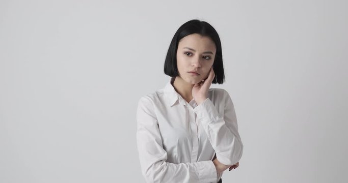Stressed young woman in thoughts over white background