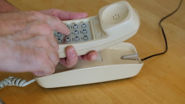 Making telephone call on vintage landline phone. Man dialing retro push button rotary dial telephone. 